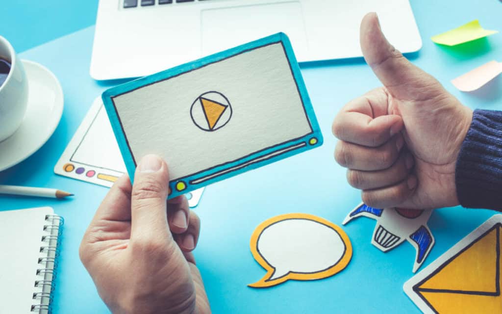 Hand Holding A Phone With A Video On The Screen And Making A Thumbs Up